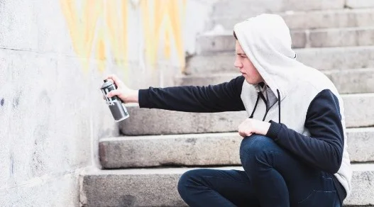 Joven pintando paredes con aerosol sin permisos