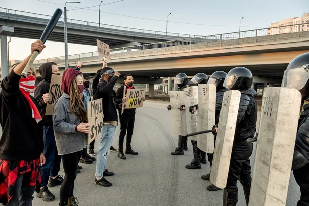 Manifestantes con carteles frente a policías con protección cuando protestar es delito en Colombia